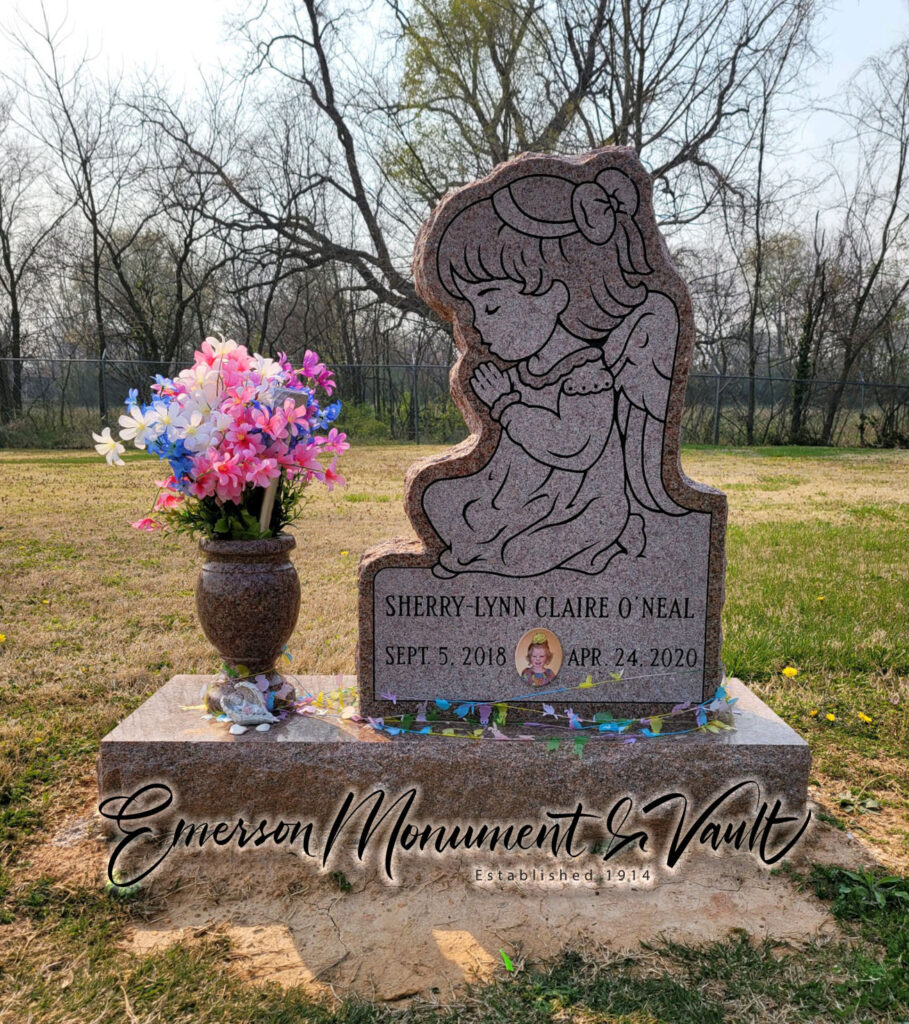 Sweet little angel memorial in Morning Rose granite with cemetery flowers in a vase.